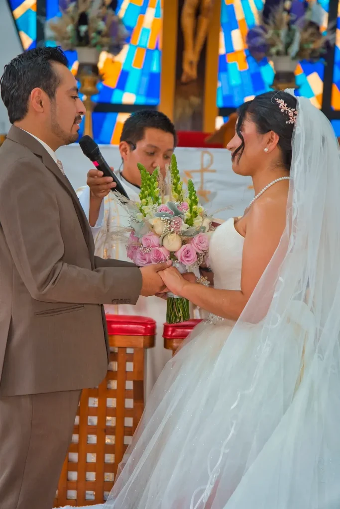 Intercambio de votos matrimoniales frente al altar en ceremonia de boda católica.