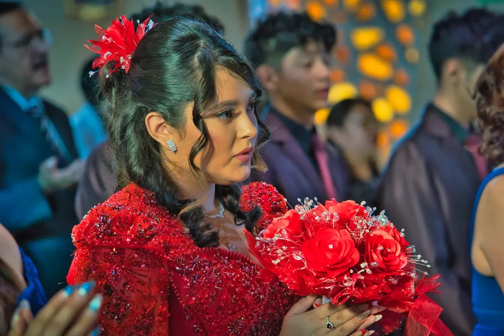 Primer plano de Valeria escuchando la ceremonia en sus XV años con vestido rojo elegante.