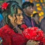 Primer plano de Valeria escuchando la ceremonia en sus XV años con vestido rojo elegante.