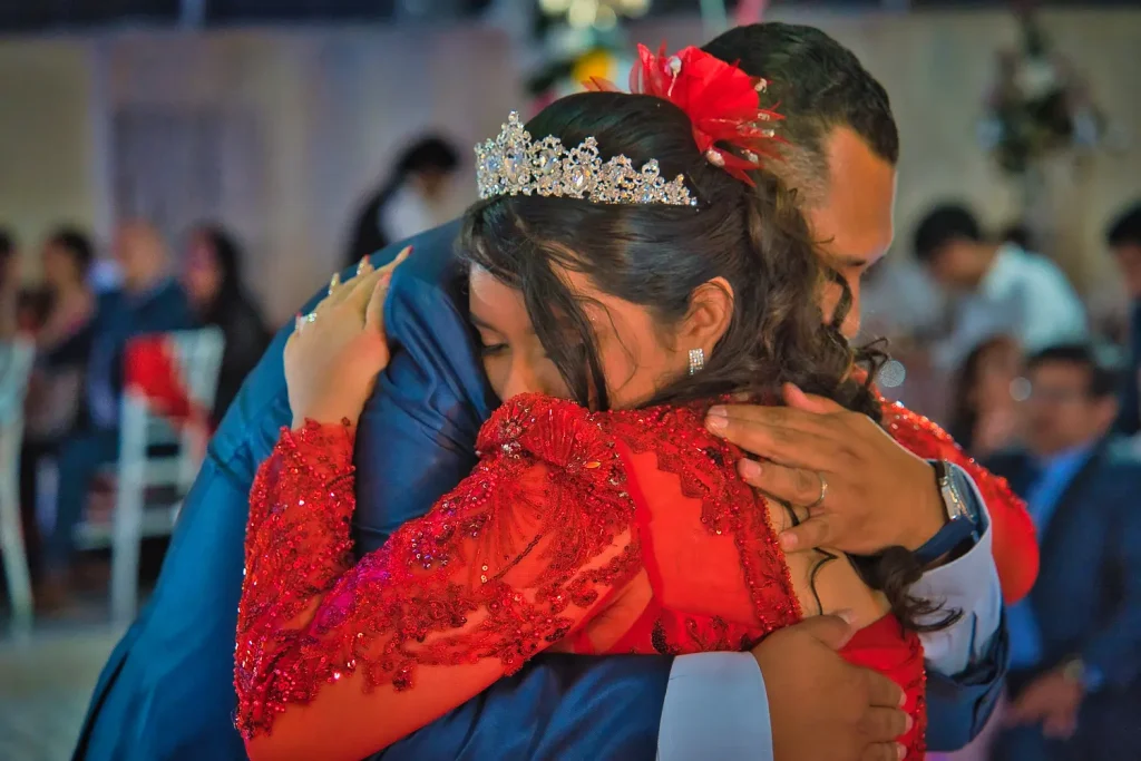 Abrazo emotivo de Valeria con su papá durante celebración de sus XV años.
