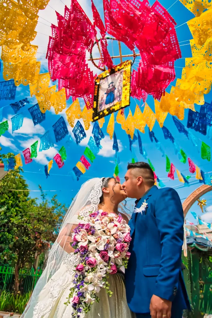 Sesión romántica de los novios bajo decoración colorida después de su ceremonia de boda.