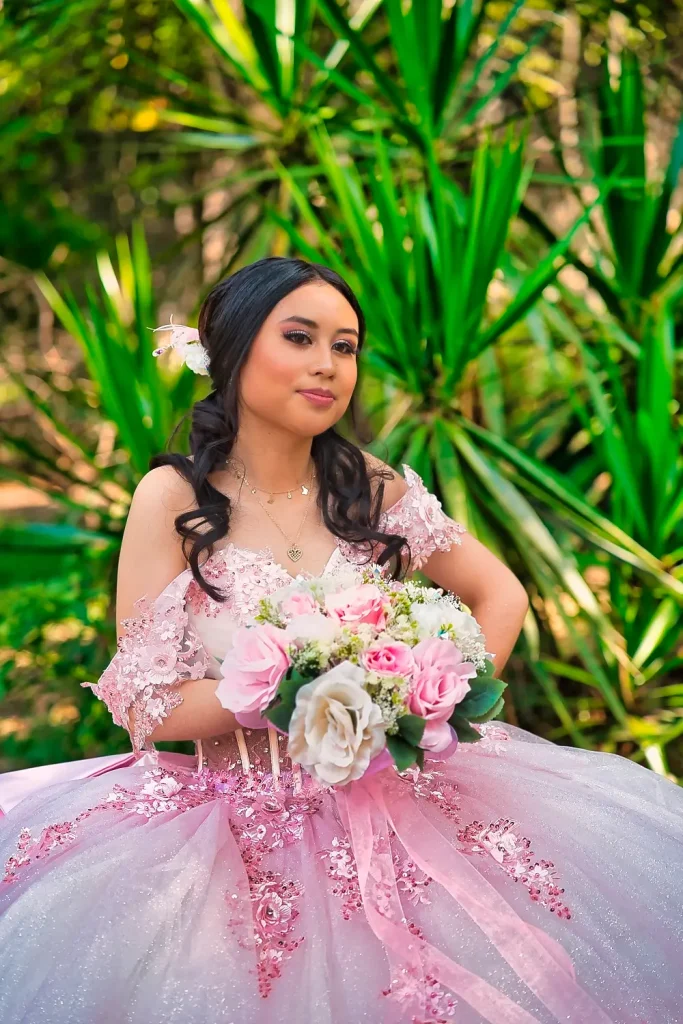 Retrato artístico de Crystal en jardín con vestido de quinceañera color rosa pastel.