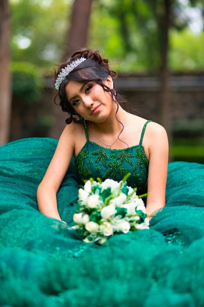 Retrato artístico de Fernanda con ramo blanco y vestido verde elegante en exteriores.