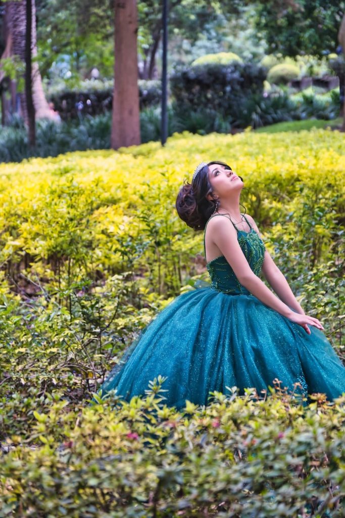 Fernanda recostada entre jardines durante sesión de XV años en Complejo Cultural Los Pinos.