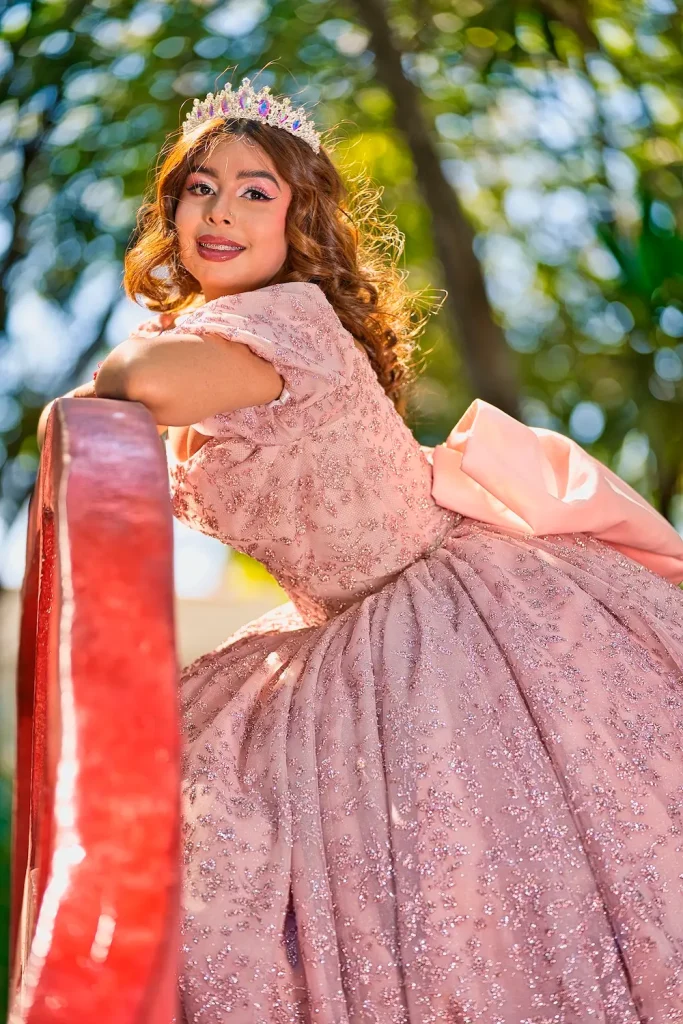 Jimena con vestido rosa de XV años posando al aire libre durante sesión fotográfica profesional.