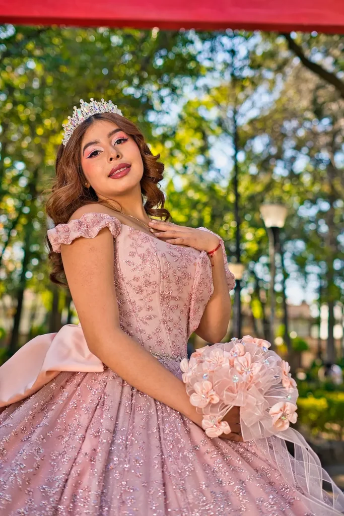Retrato de Jimena sonriendo con vestido de quinceañera en jardín con luz natural.