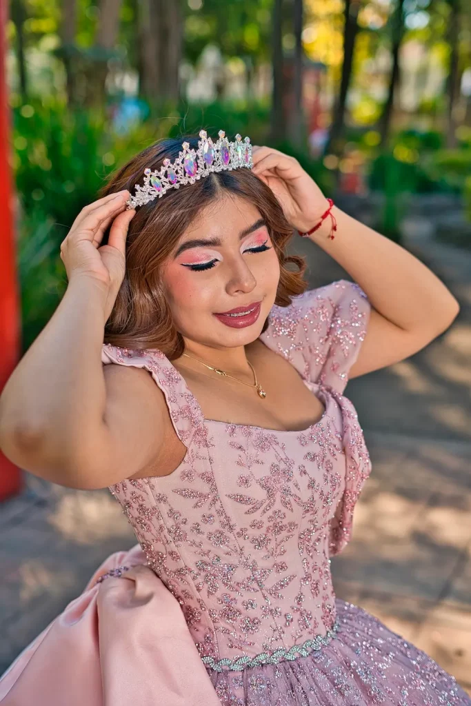 Quinceañera Jimena acomodando su tiara durante sesión de fotos en exterior.