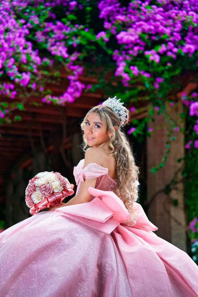 Megan con vestido rosa de XV años posando entre flores moradas en sesión fotográfica en Parque México.
