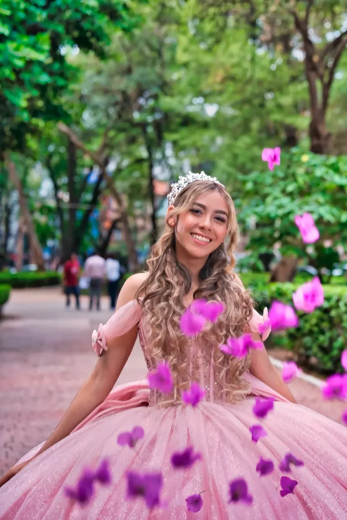 Megan sonriendo en sendero de Parque México con pétalos flotando durante sesión de XV años.