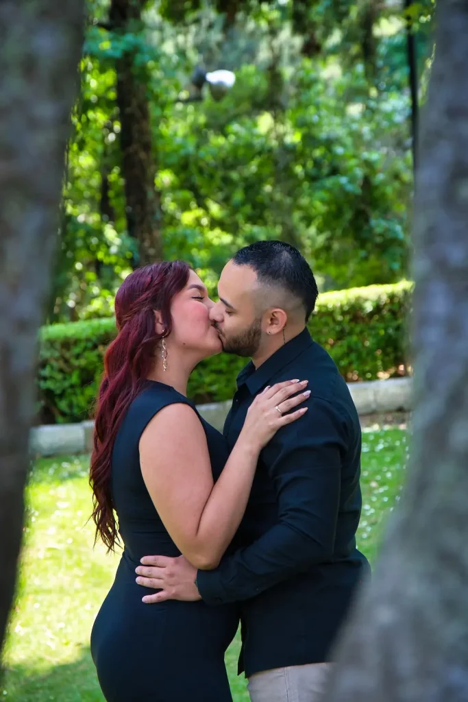 Beso romántico de los futuros esposos durante una sesión prematrimonial rodeada de naturaleza.
