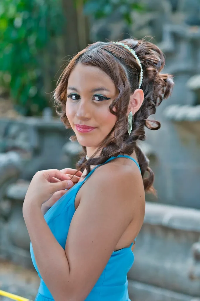 Primer plano de quinceañera Dany junto a fuente de piedra en sesión exterior.