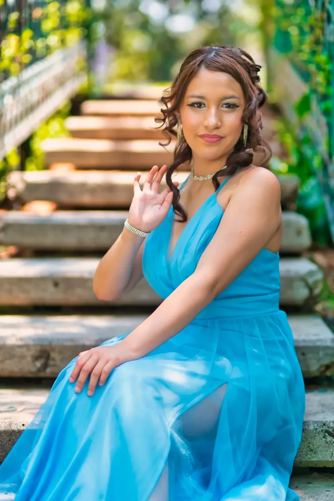 Quinceañera Dany sentada en escalinata rodeada de vegetación en sesión profesional.