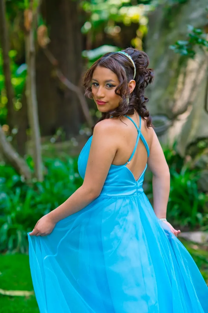 Dany mostrando vestido de quinceañera azul en sesión fotográfica en jardín.